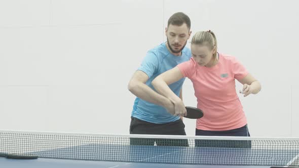 Concentrated Female Coach Showing Right Movement of Hand in Ping-pong To Young Caucasian Man