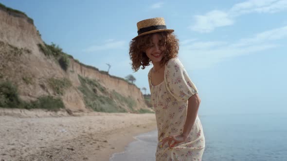 Cute Curly Girl Dancing on Ocean Waves Holding Dress