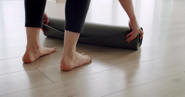 Closeup Attractive Woman Unfolds a Rug for Practicing Yoga at Home