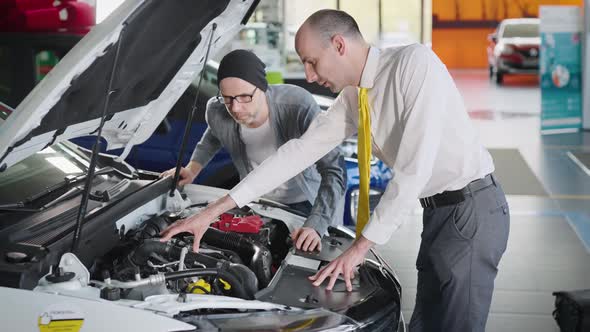 Sales Manager and Client Near a New Car with an Open Hood