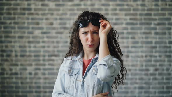 Portrait of Beautful Trendy Girl Raising Sunglasses Staring Looking Surprised