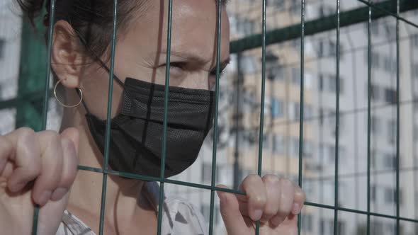 Woman in quarantine by bars. 