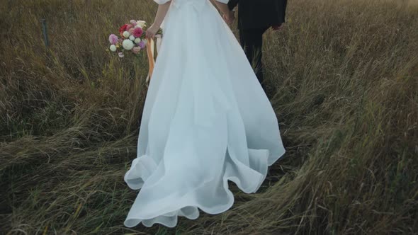 The Newlyweds Stand in Nature with Their Heads Bowed to Each Other and the Groom Kisses the Bride