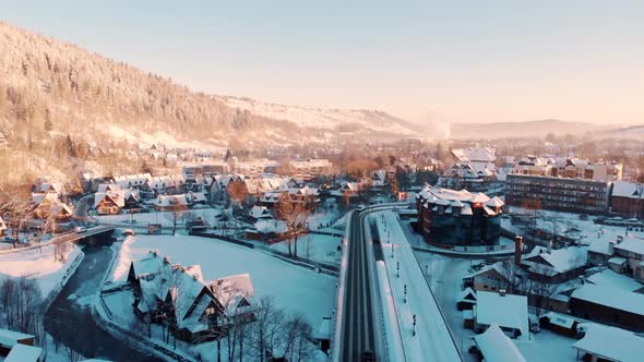 Aerial View Of Vehicles Moving On A Bridge With SnowCovered Houses On Sides