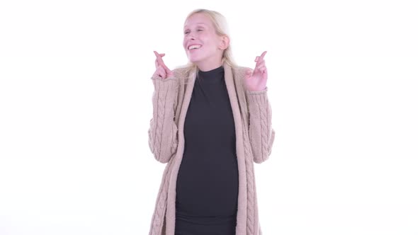 Happy Young Blonde Pregnant Woman Wishing with Fingers Crossed