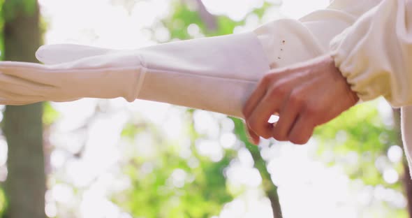 Closeup Right Hand of Male Beekeeper in White Protective Suit Wears a White Protective Glove and