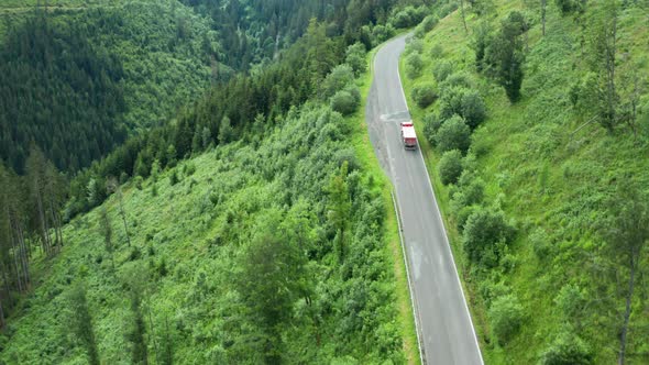 Aerial View of the Road with Driving Cars and Truck in the Mountains with High Green Fir Foliar Pine