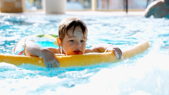 Little Boy Swimming In The Pool With Rubber Ring