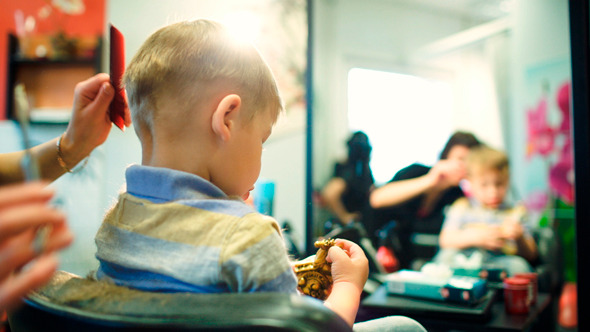 Hairdresser Cutting Childs Hair While He Playing 