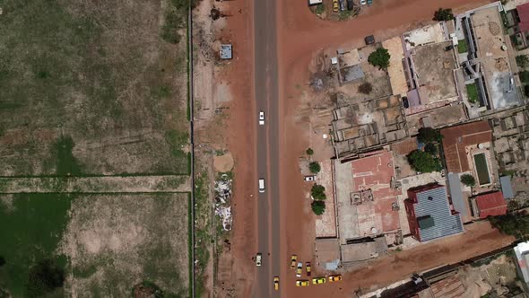 Aerial bird's eye view tracking a white van on Kololi Road in Serrekunda Africa with red dusty roads