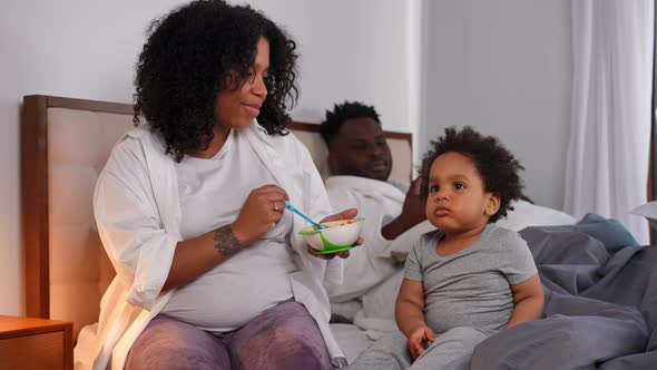 Hyperactive Toddler Boy Sitting on Bed with Woman Feeding Child Talking