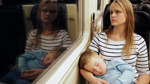 Tired Woman In The Train With Sleeping Son On Her 