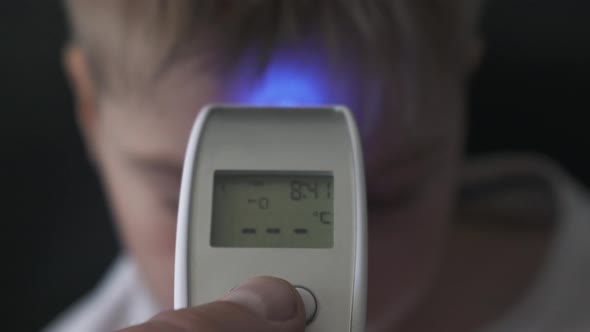 Dad Taking Sons Temperature Using a Digital Thermometer Covid 19 Virus Symptom, display 37.6 Degrees