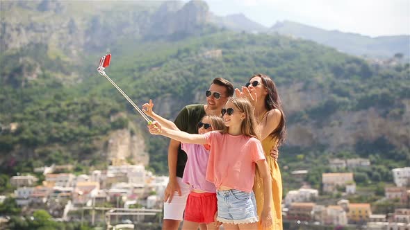 Parents and Kids Taking Selfie Photo Background Positano Town in Itali on Amalfi Coast