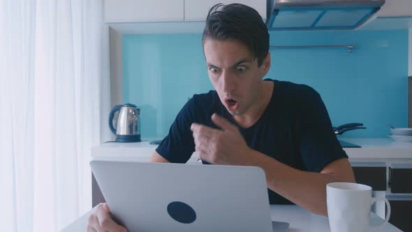 Scared Man is Shocked and and Surprised By What He Saw in the Laptop While Sitting at Home Kitchen