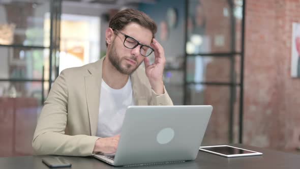 Young Man with Laptop Having Headache
