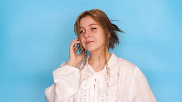 Cheerful attractive Caucasian young brunette woman 20 years old talking on the phone. Studio shot on