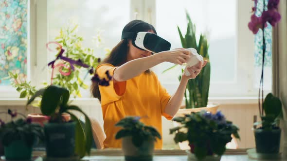 Emotional woman in VR glasses and playing at computer game with joystick.