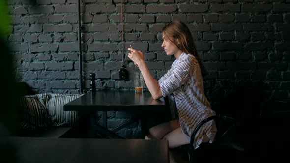 Beautiful Woman Using Smartphone and Drinking Coffee in the Cafe