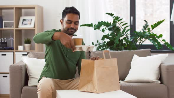 Indian Man with Takeaway Coffee and Food at Home