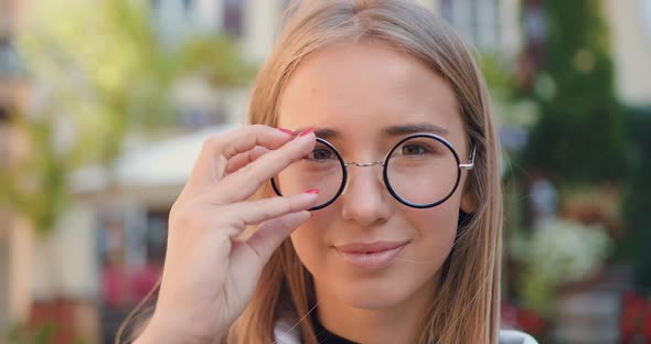 Young Light-Haired Woman which Putting on Stylish Glasses while Posing on camera