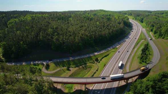 4K Drone Footage Of Highway Overpass With Trucks In Forest Environment.