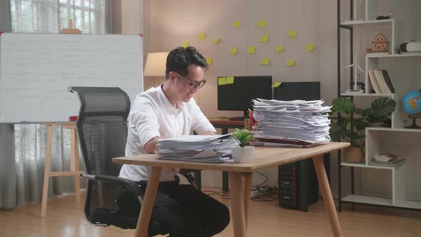 Smiling Asian Man Enjoys Working With Documents At The Office