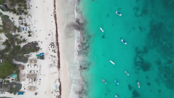 Top drone shot over a shoreline beach in Tulum, Mexico. Beach with cafes, restaurants, hotels. Boats