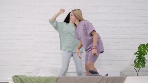 Young Girls Dancing on the Bed at Home