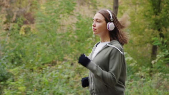 Woman in Earphones Jogging in Nature in Slow Motion