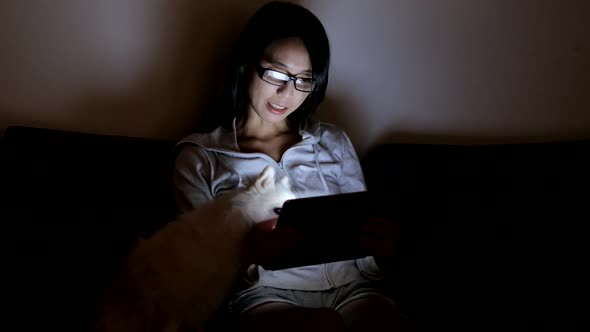 Woman looking at tablet with her dog at night 