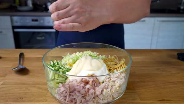 Woman Adds Salt Into a Bowl of Fresh Vegetables and Chicken Salad