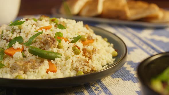 Sprinkling Greenery on Couscous with Chicken on Table Closeup