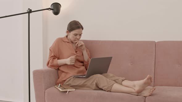 Young Woman with Laptop on Sofa