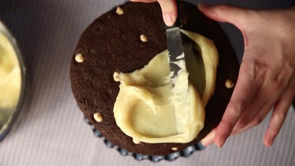 Spreading a cream filling between layers of a chocolate cake - top down view