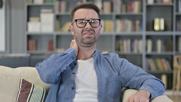 Portrait of Tired Young Man Having Neck Pain on Sofa 