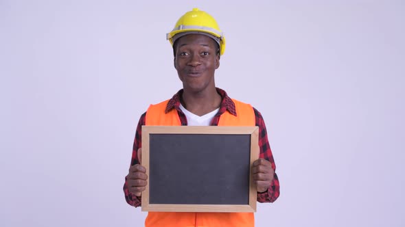 Young Happy African Man Construction Worker Holding Blackboard and Looking Surprised