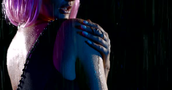 Portrait in Profile of a Woman with Pink Hair and a Black Swimsuit in the Rain in the Dark