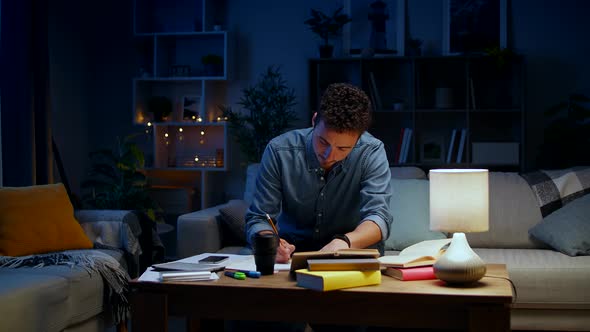 Young Man Dancing While Sitting on a Couch While Studying at Night