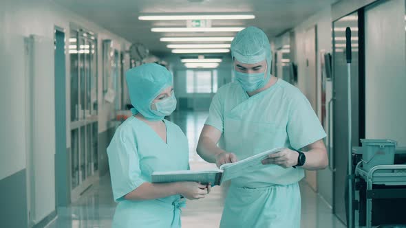 Two Surgeons are Looking Through Medical Documents in the Hall