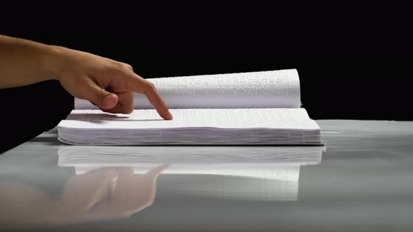 Man Fingers Read Braille Writing. Black Background. Side View