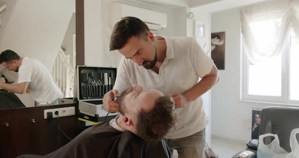 Professional Barber Shaves Customer Beard with Straight Razor