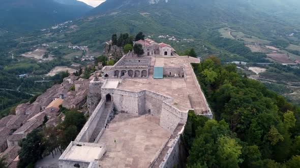 Aerial pan forward shot of a fort on top of a small town in Italy