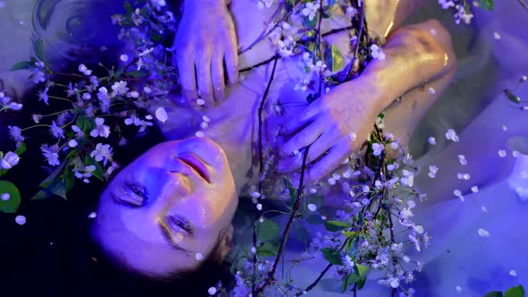 Stunning Portrait of Woman with Flowers in Water Cold Violet Colors in Night Magic and Mystery