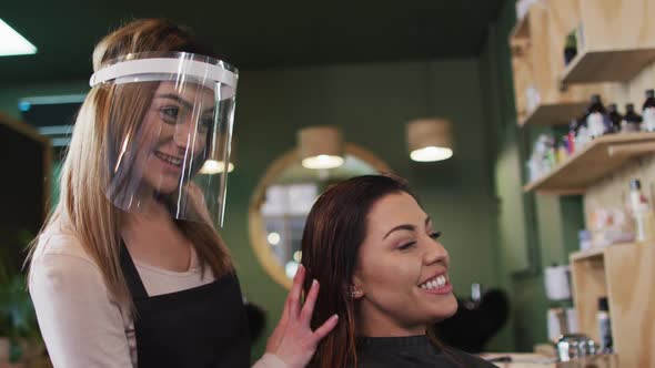 Female hairdresser running her fingers through hair of female customer
