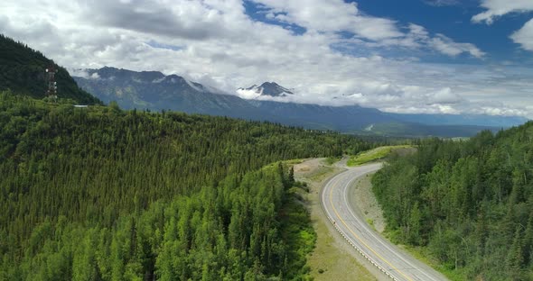 Winding Mountain Road, Dense Forest and High Mountain Range Covered with Clouds