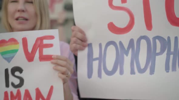 Camera Moves Along Row of Anti-homophobia Posters. Caucasian Activists with Banners Shouting on