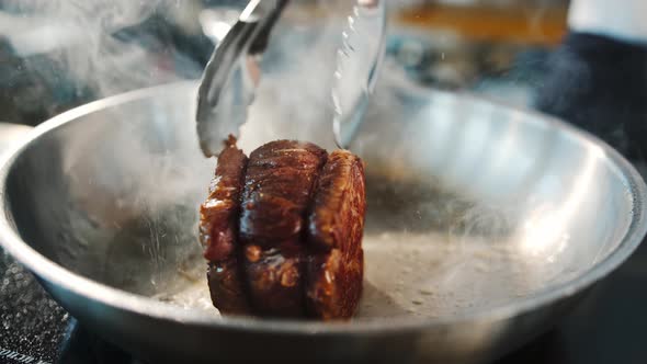 Close-up of a filet mignon being cooked in a frying pan