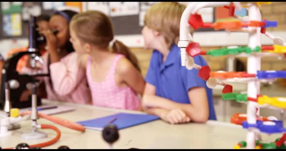 School kids looking through microscope in laboratory