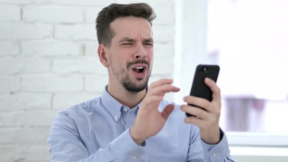 Shocked Creative Man Reacting To Loss on Smartphone